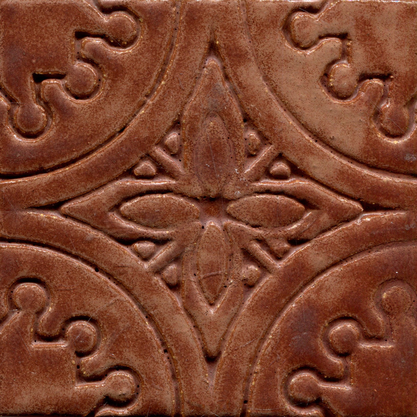 A collection of matte brown stamped tiles with a floral pattern.