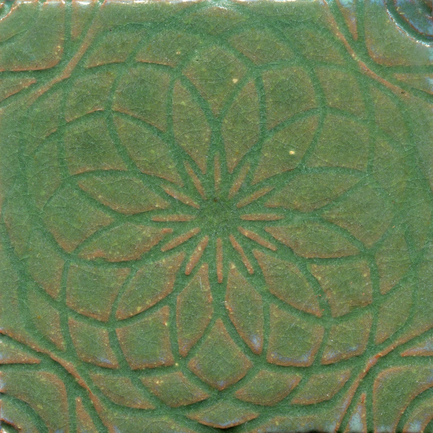 Green stamped tile with a geometric floral pattern.