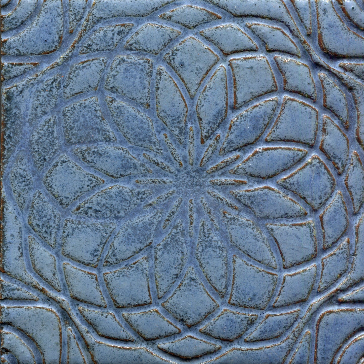 Matte mottled blue stamped tile with a geometric floral pattern.