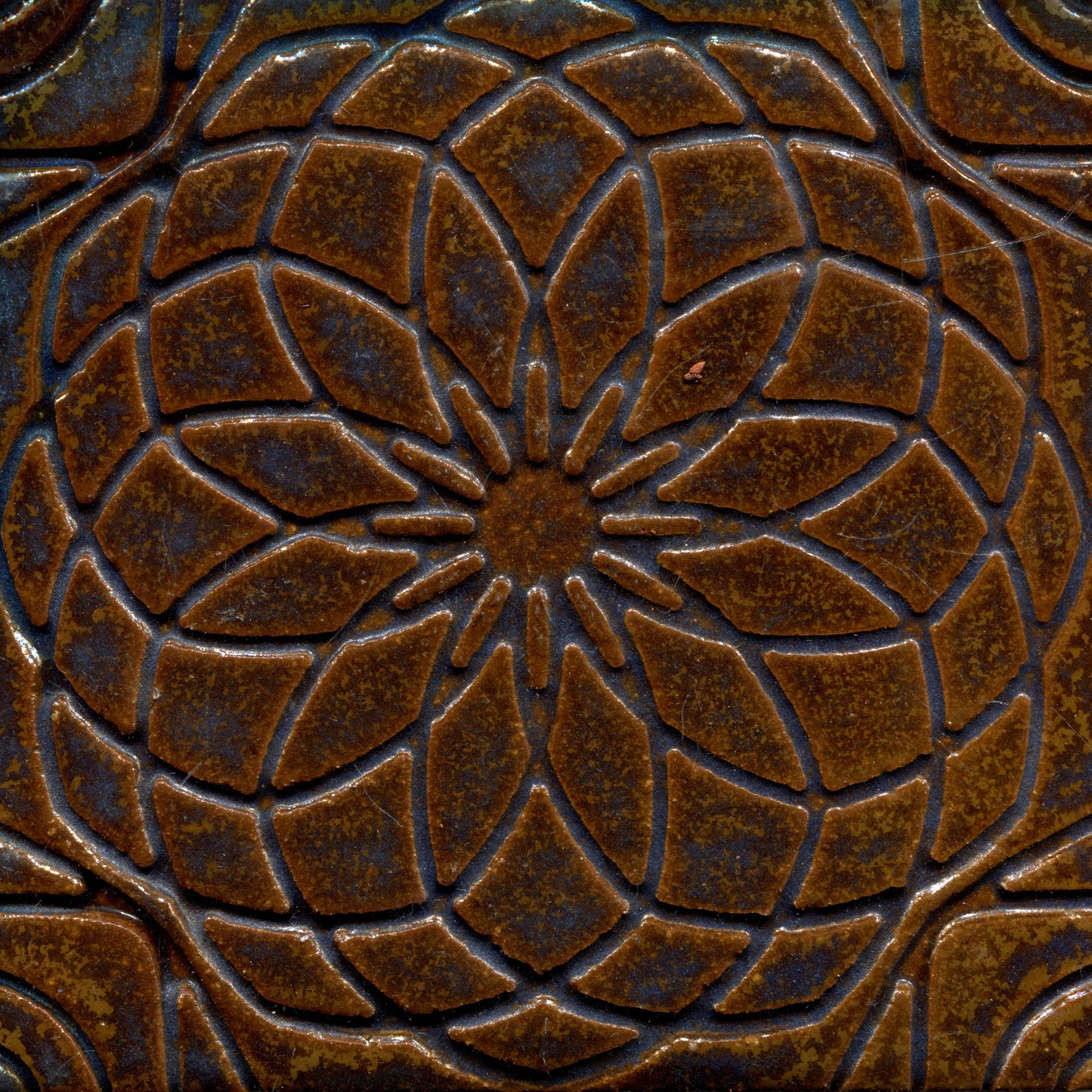 Copper brown stamped tile with a geometric floral pattern.