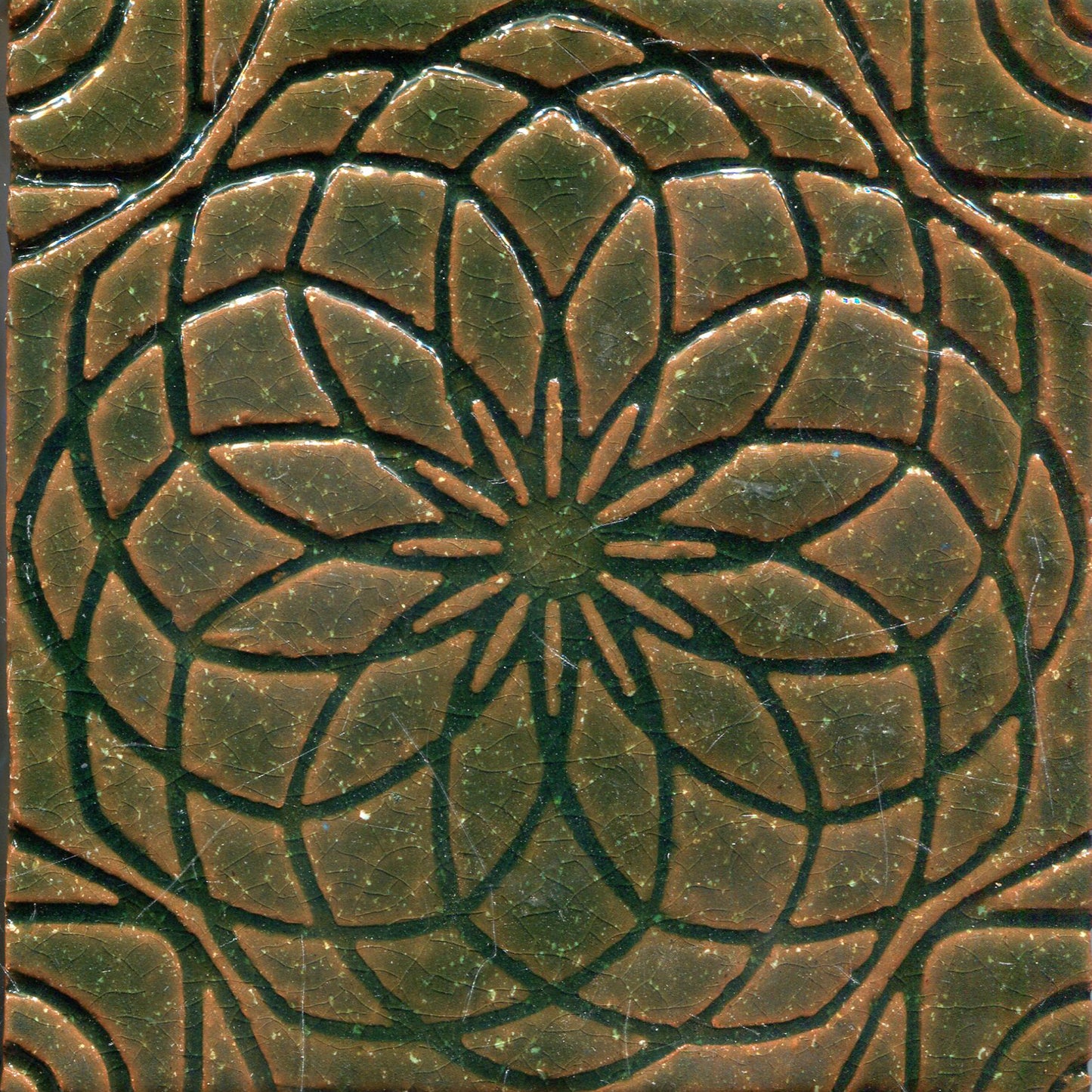 Green stamped tile with a geometric floral pattern.