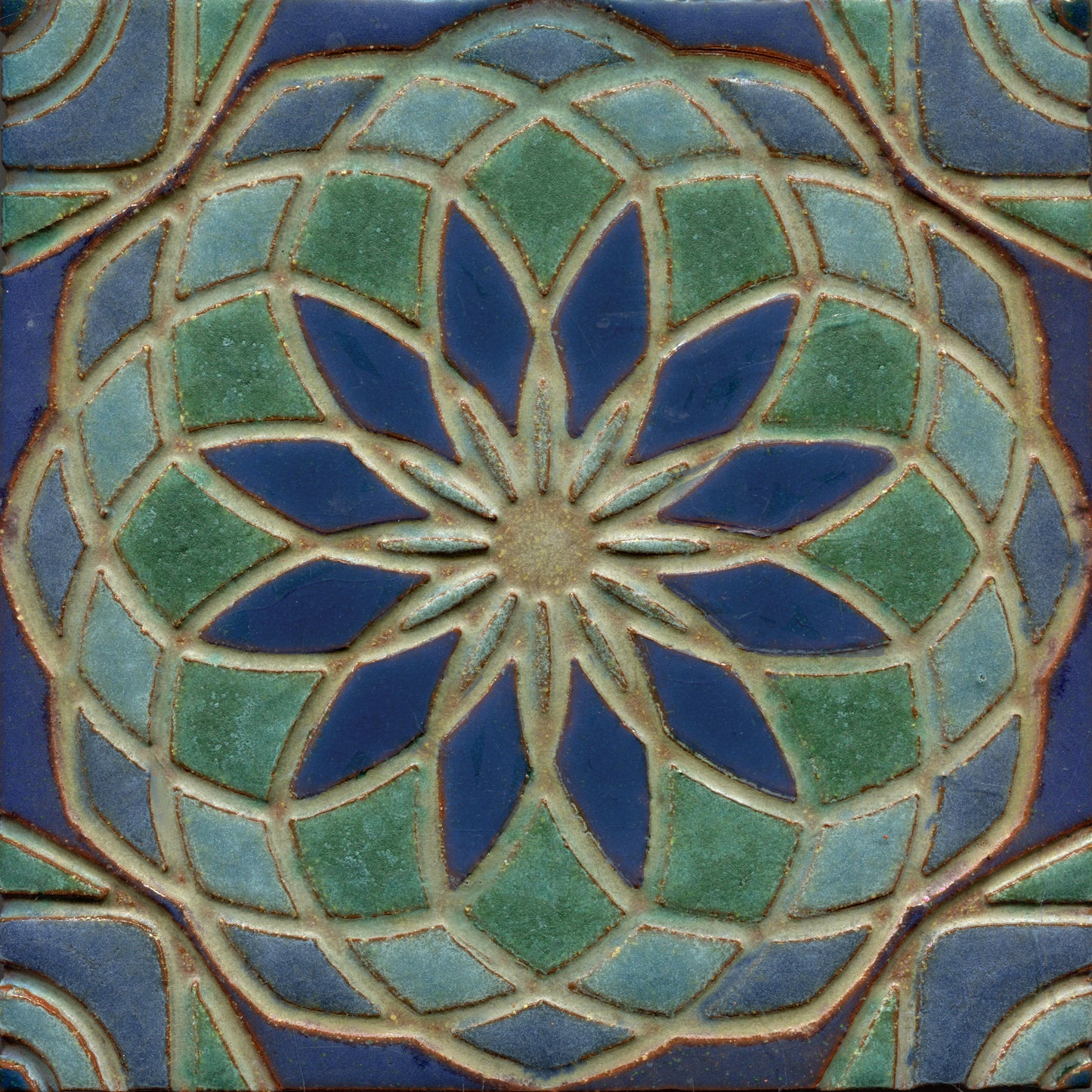Blue and green stamped tile with a geometric floral pattern.