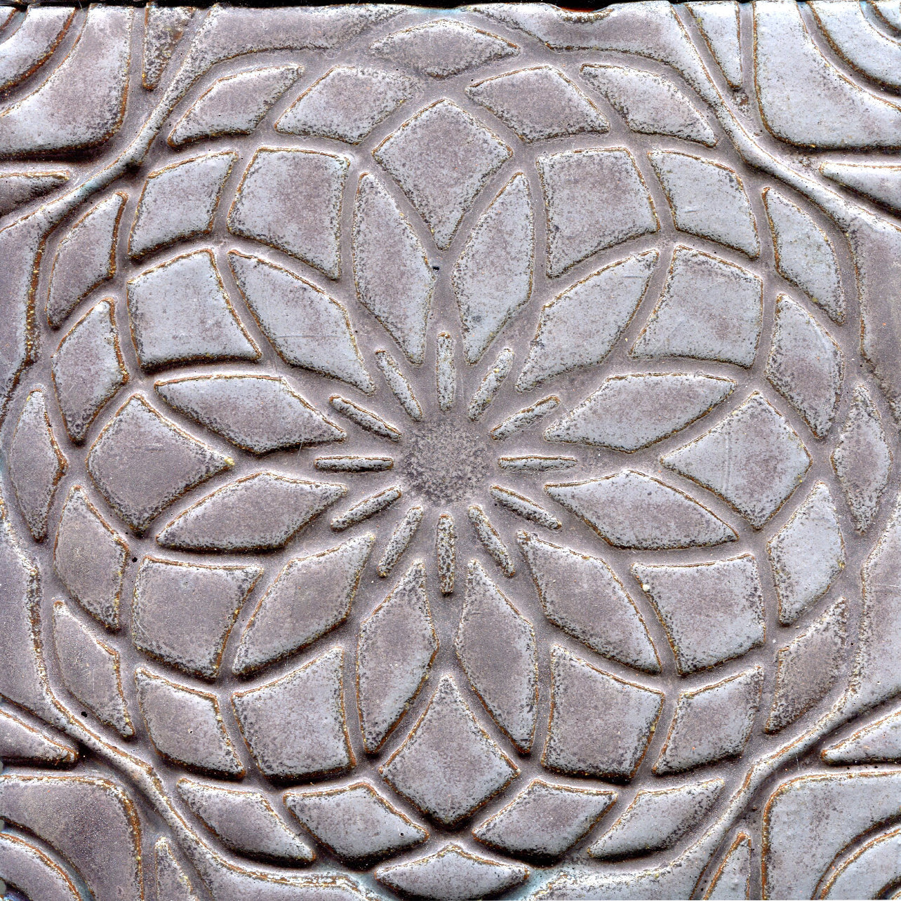 Grey stamped tile with a geometric floral pattern.
