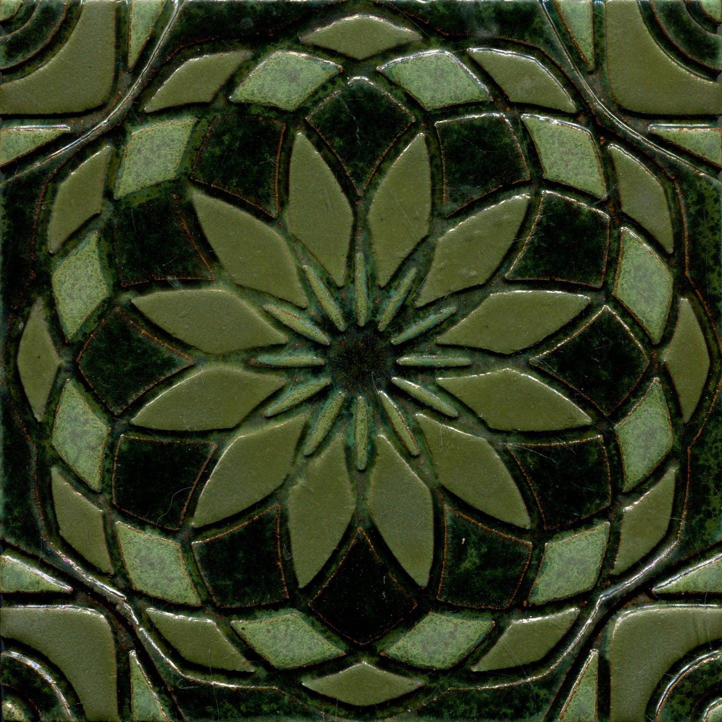 Green stamped tile with a geometric floral pattern.