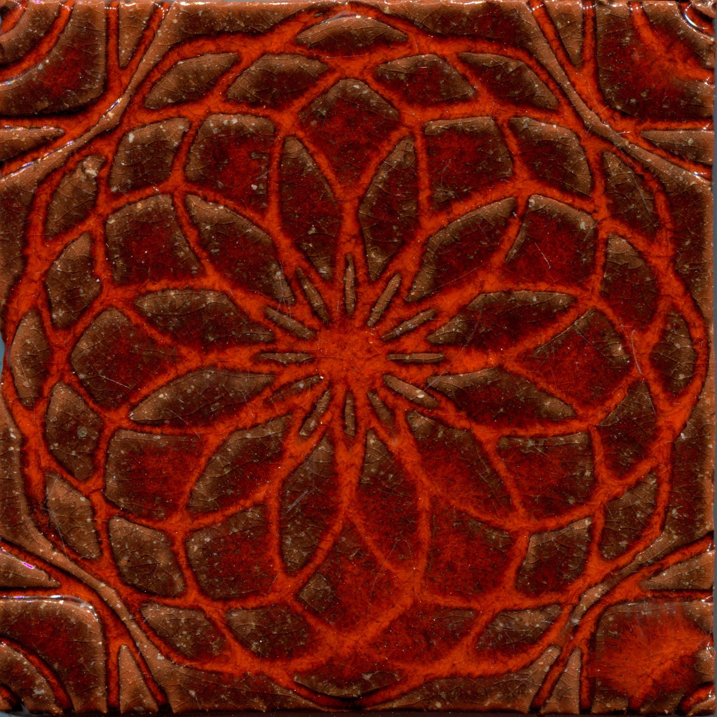 Orange glazed stamped tile with a geometric floral pattern.