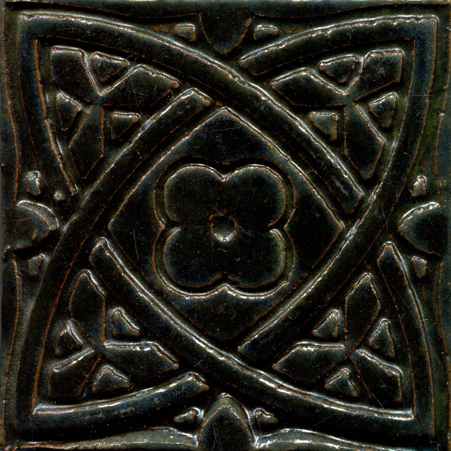 Dark green stamped tiles with a Celtic geometric pattern.