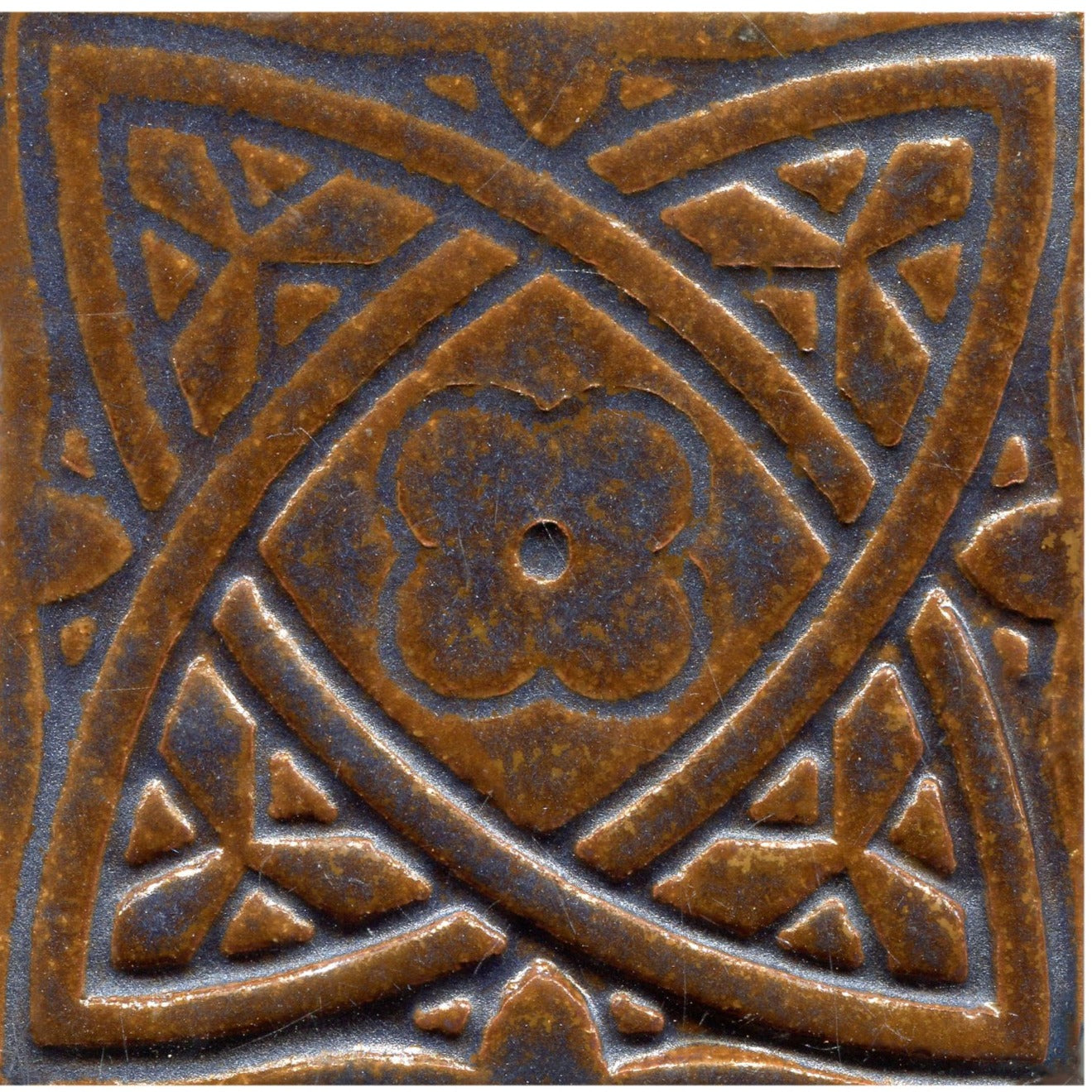 Copper brown stamped tiles with a Celtic geometric pattern.