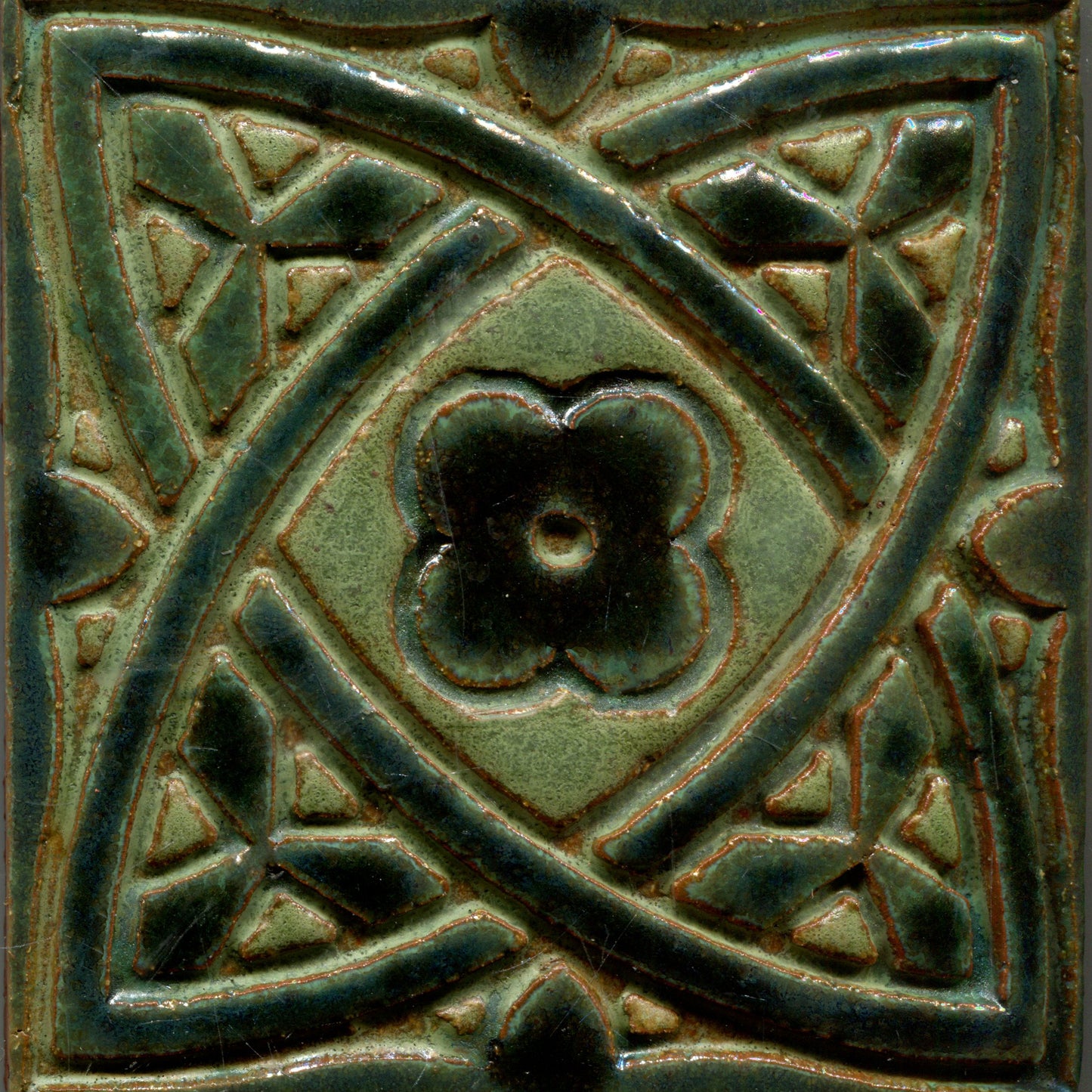 A collection of green stamped tiles with a Celtic geometric pattern.