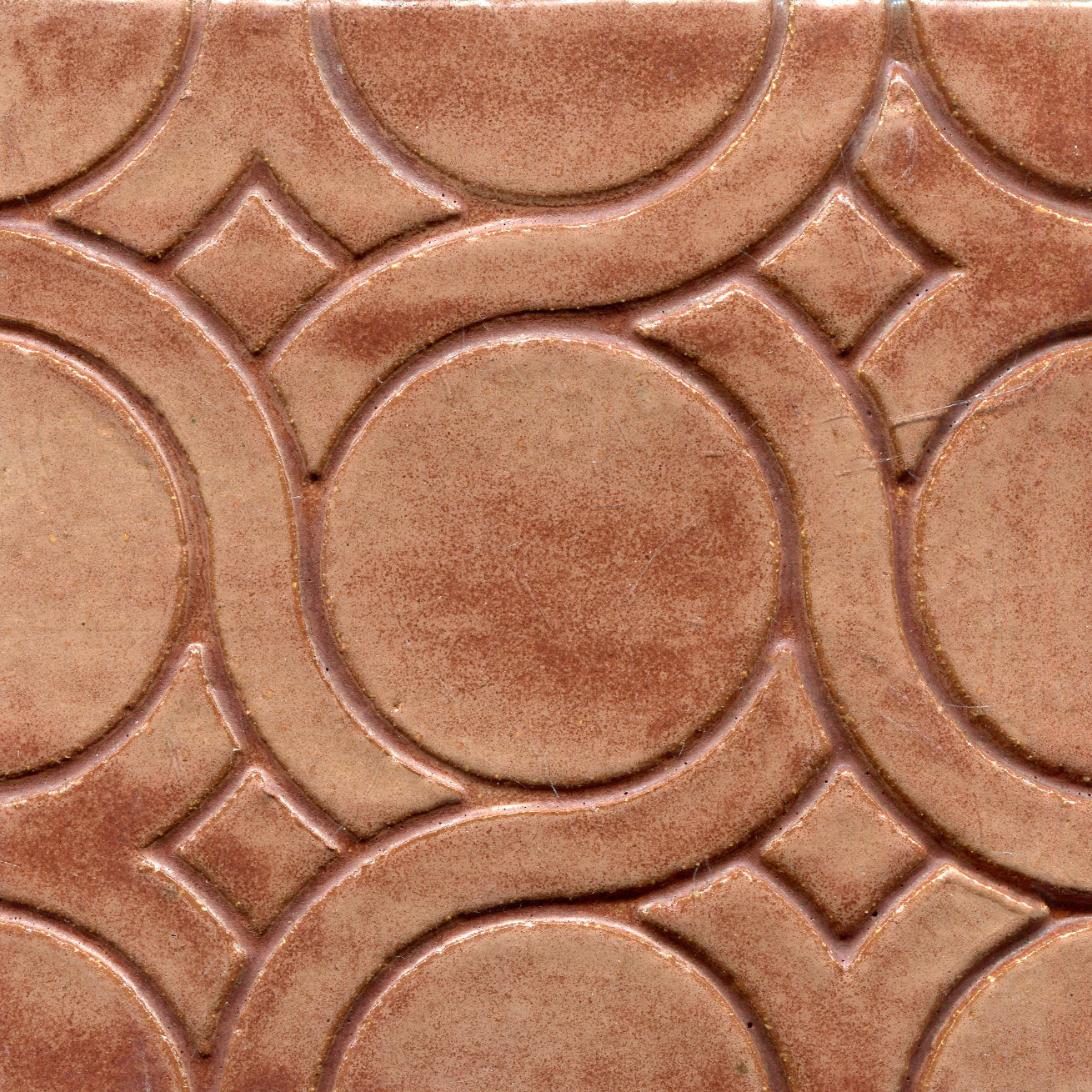 A pattern of woven knots on stamped tiles, with brown colors creating a geometric design.