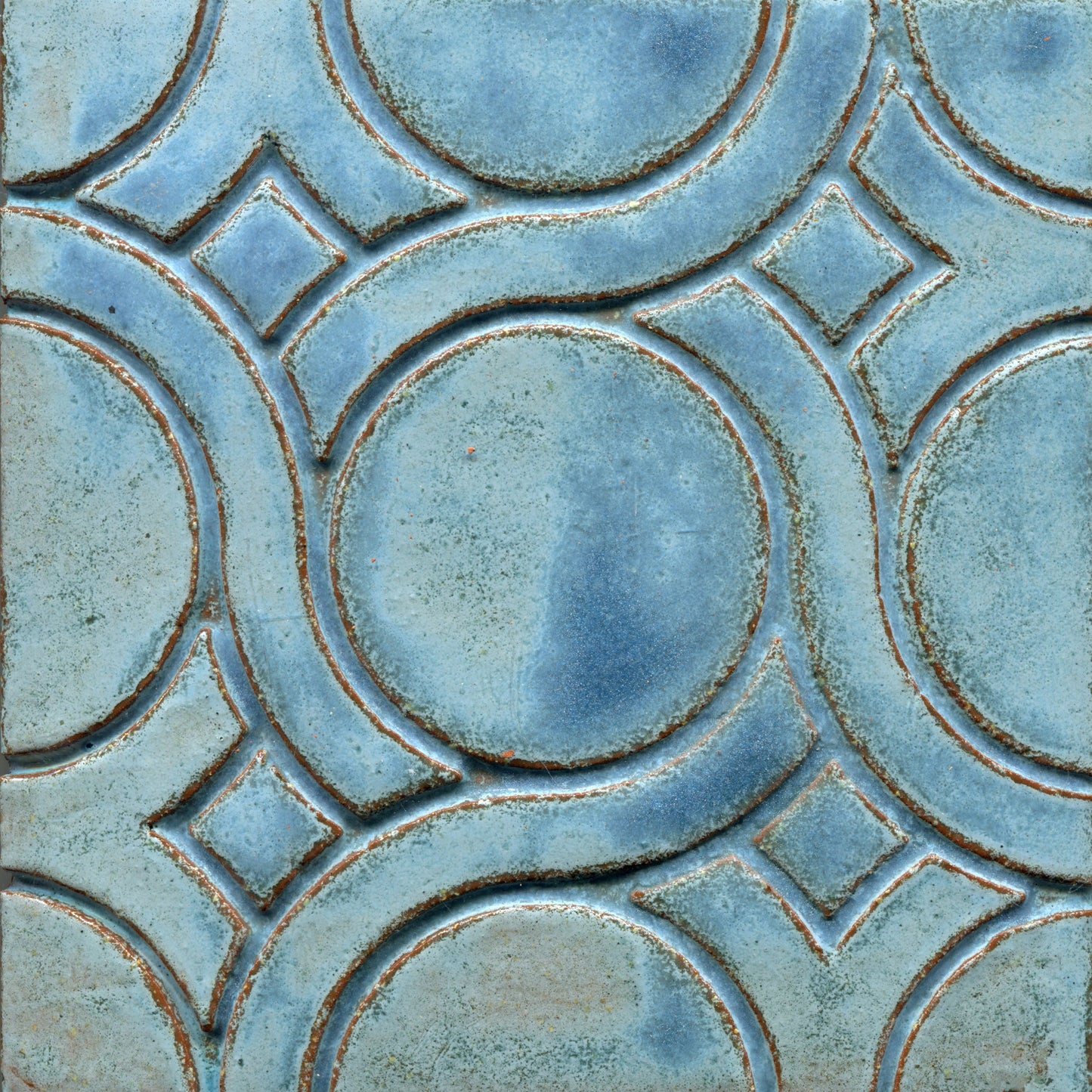 A pattern of woven knots on stamped tiles, with blue coloring creating a geometric design.