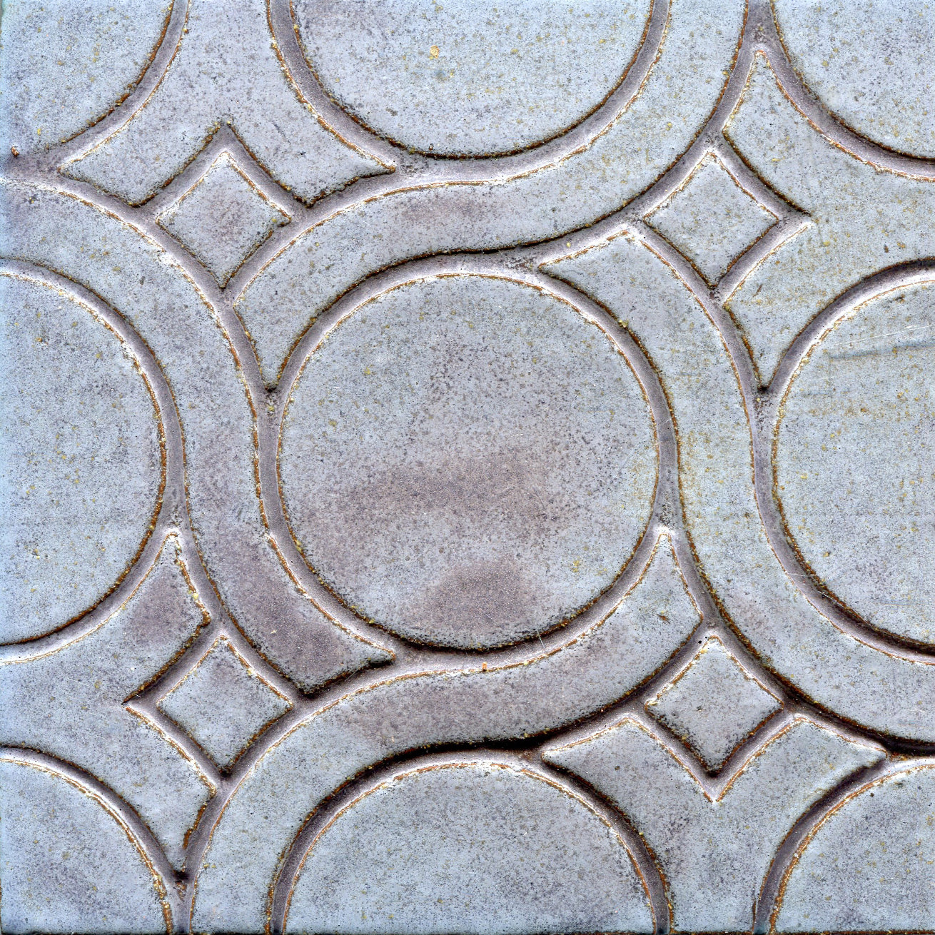 A pattern of woven knots on stamped tiles, with grey colors creating a geometric design.