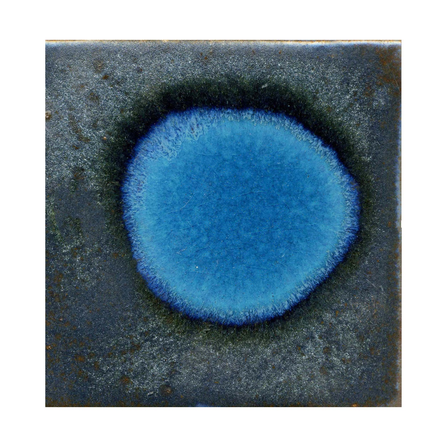 A ceramic artwork with a blue metallic spot and a surrounding darker blue texture on a darker background.