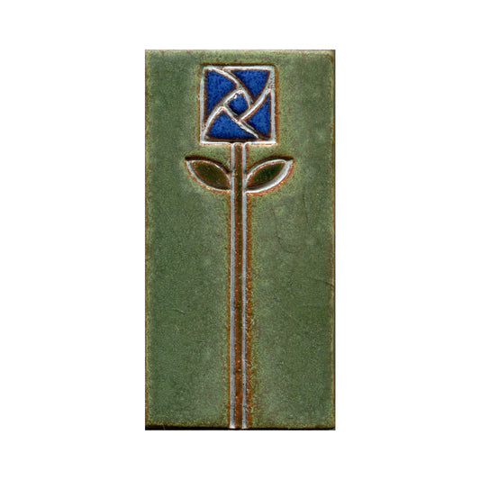 A rectangular ceramic tile with a stamped floral design in the center, featuring blue petals and green leaves